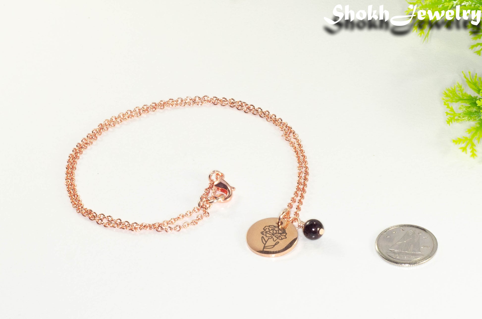 Rose Gold Plated January Birth Flower Necklace with Garnet Birthstone Pendant beside a dime.