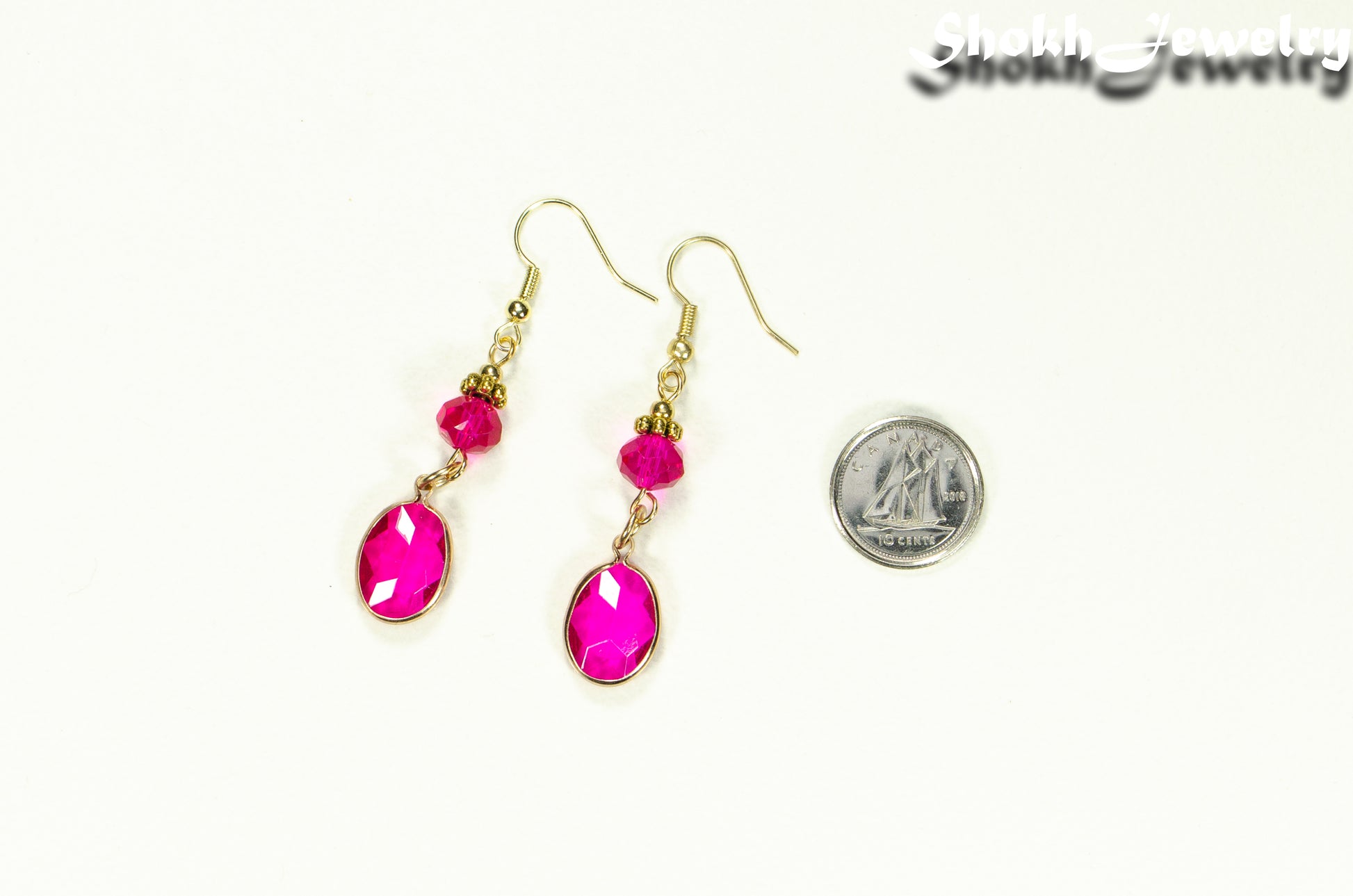 Hot Pink Oval Glass Dangle Earrings beside a dime.