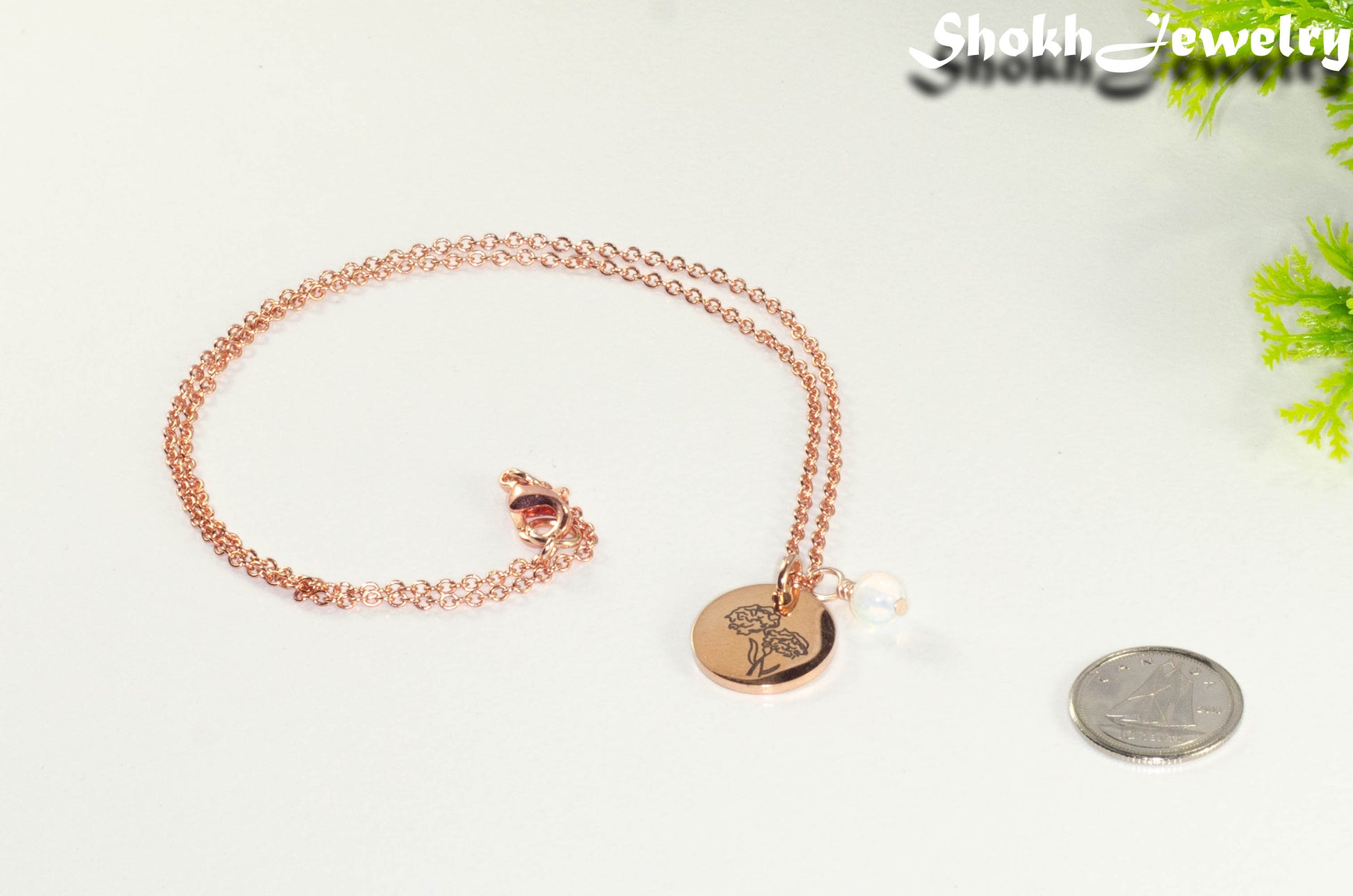 Rose Gold Plated October Birth Flower Necklace with White Opal Birthstone Pendant beside a dime.