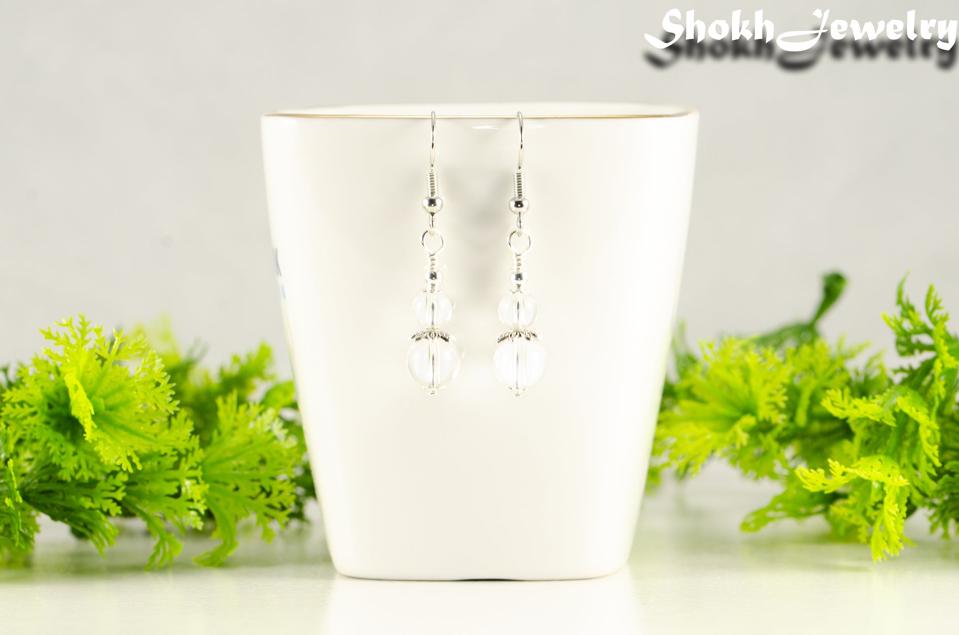 Small Clear Quartz Earrings displayed on a tea cup.