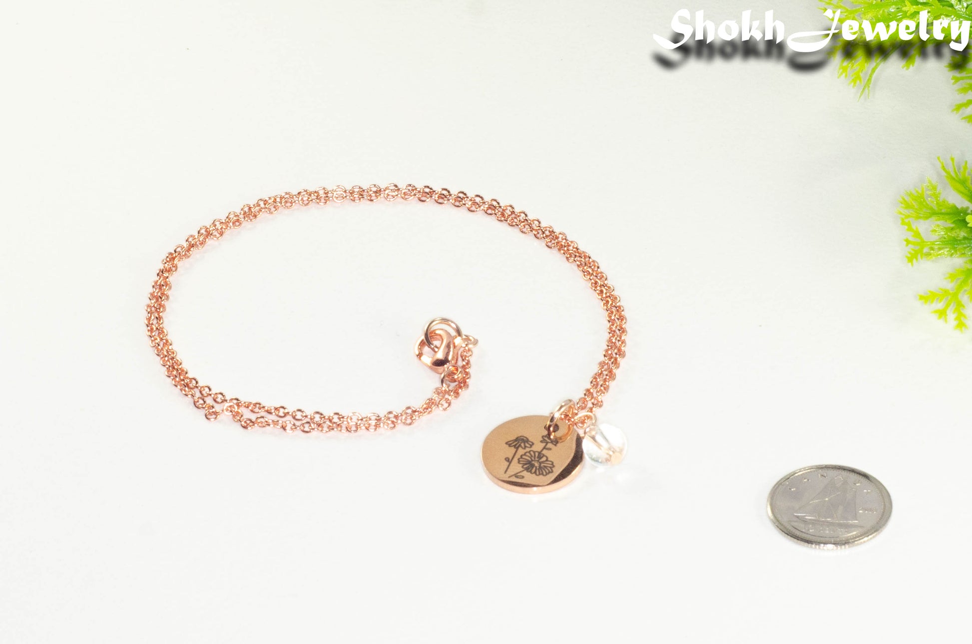 Rose Gold Plated April Birth Flower Necklace with Clear Quartz Birthstone Pendant beside a dime.