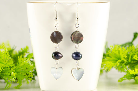 Grey Seashell and Black Pearl Earrings displayed on a tea cup.