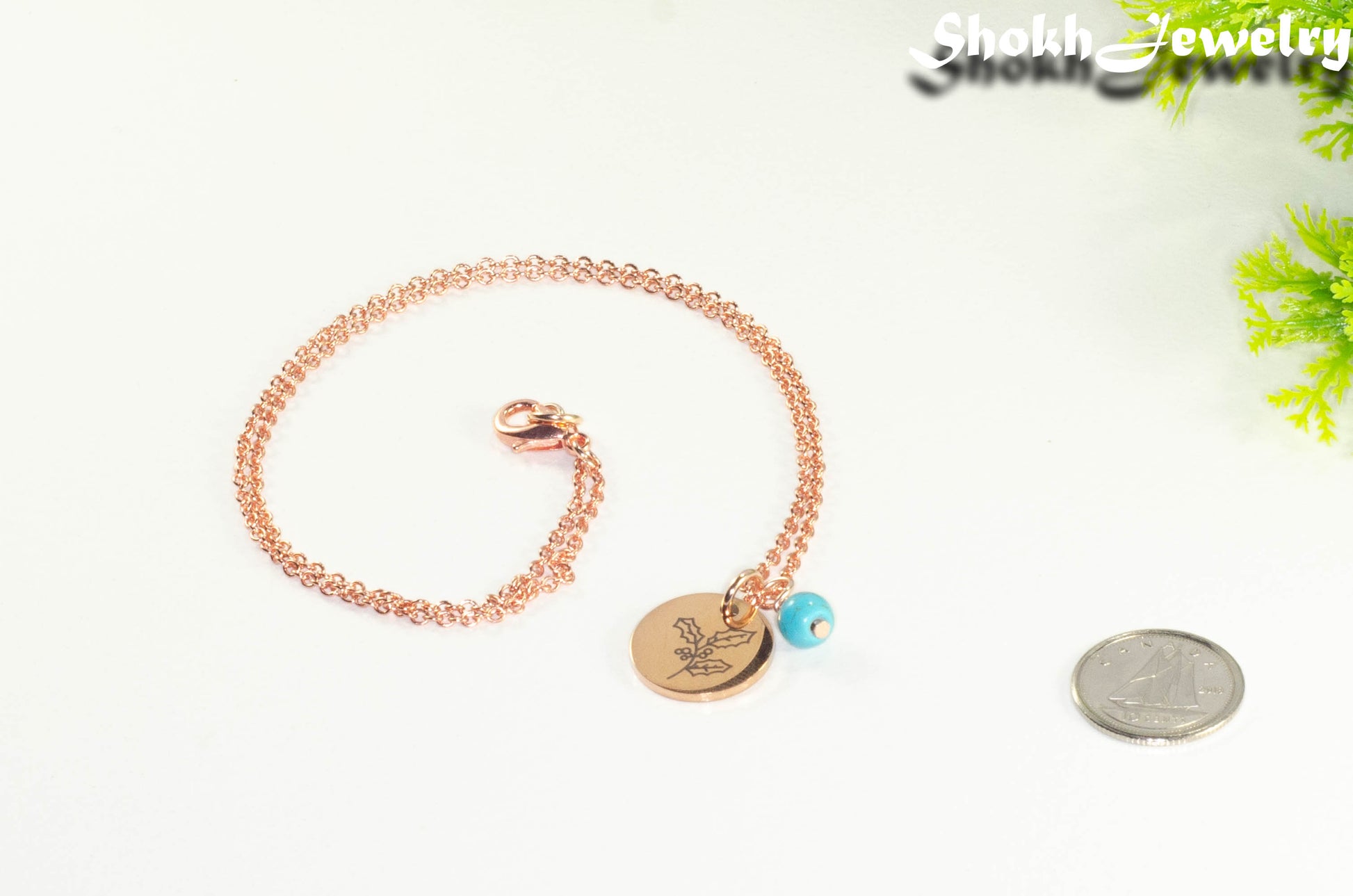 Rose Gold Plated December Birth Flower Necklace with Turquoise Howlite Birthstone Pendant beside a dime.