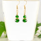 Small Dark Green Glass Bead Dangle Earrings displayed on a tea cup.