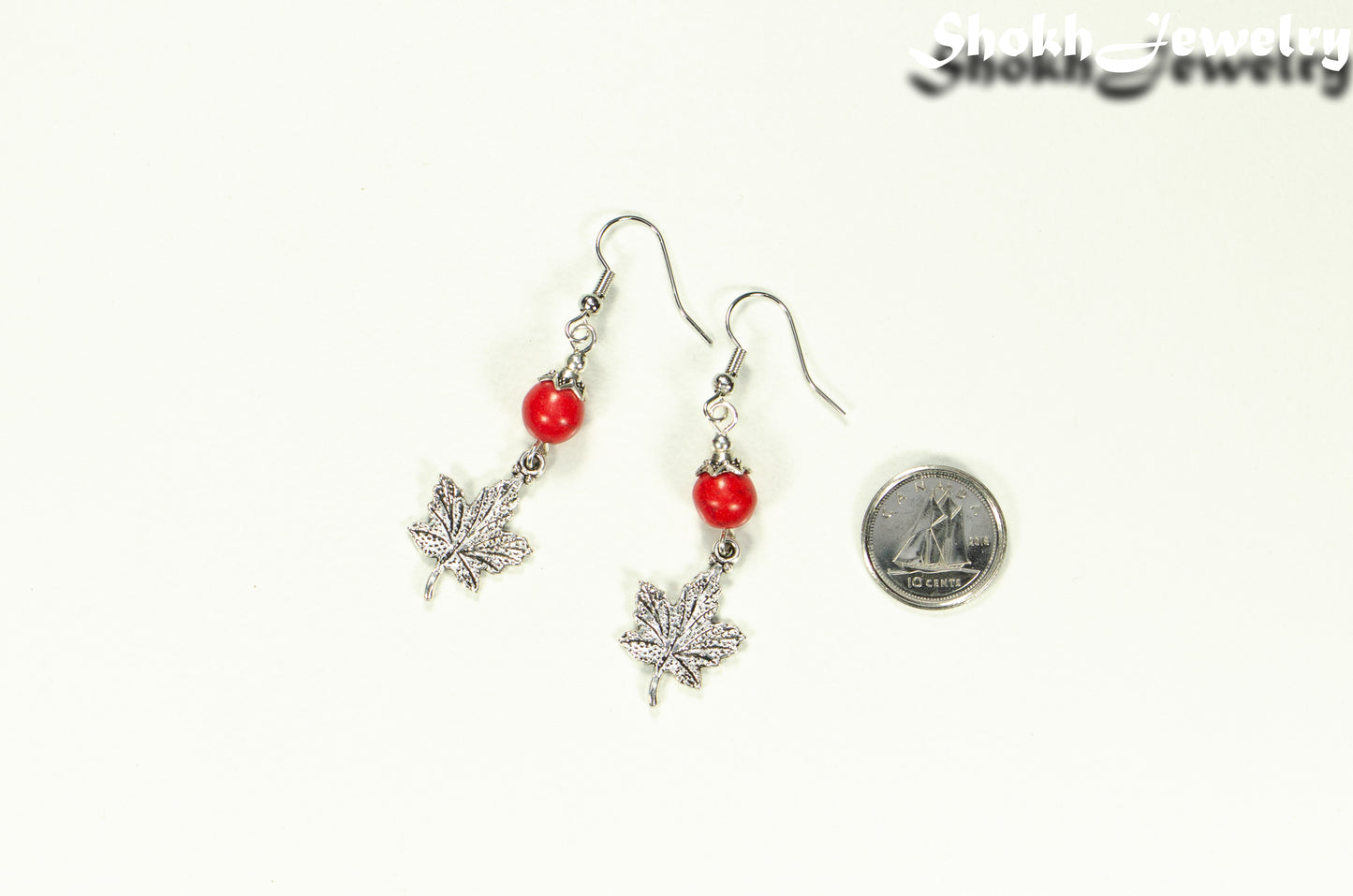 Red Howlite and Tibetan Silver Maple Leaf Dangle Earrings beside a dime.