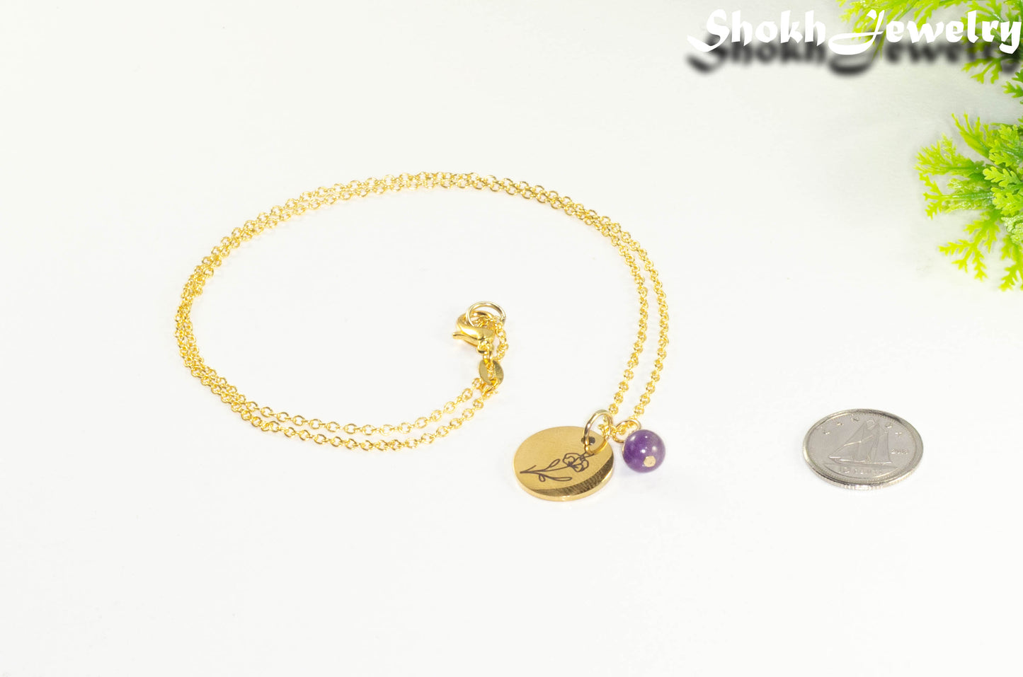 Gold Plated February Birth Flower Necklace with Amethyst Birthstone Pendant beside a dime.