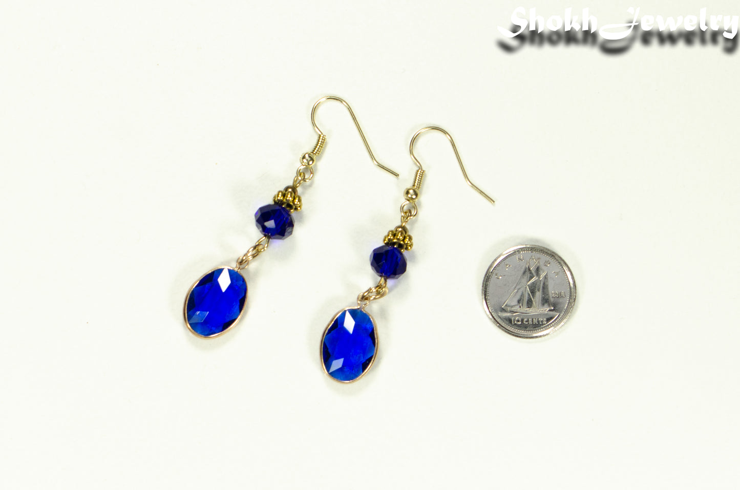 Navy Blue Oval Glass Dangle Earrings beside a dime.