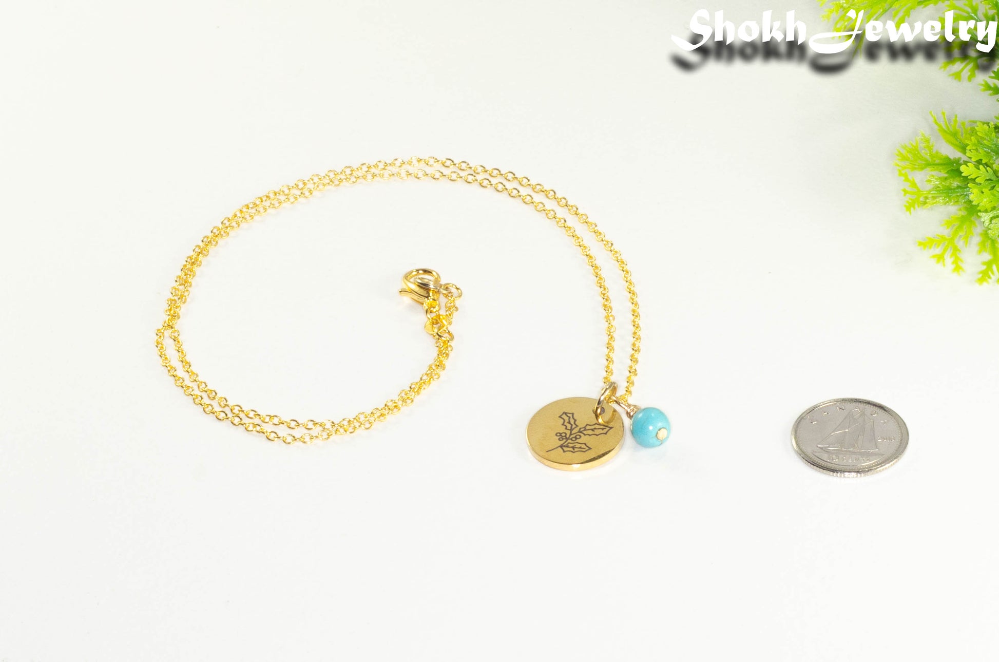 Gold Plated December Birth Flower Necklace with Turquoise Howlite Birthstone Pendant beside a dime.