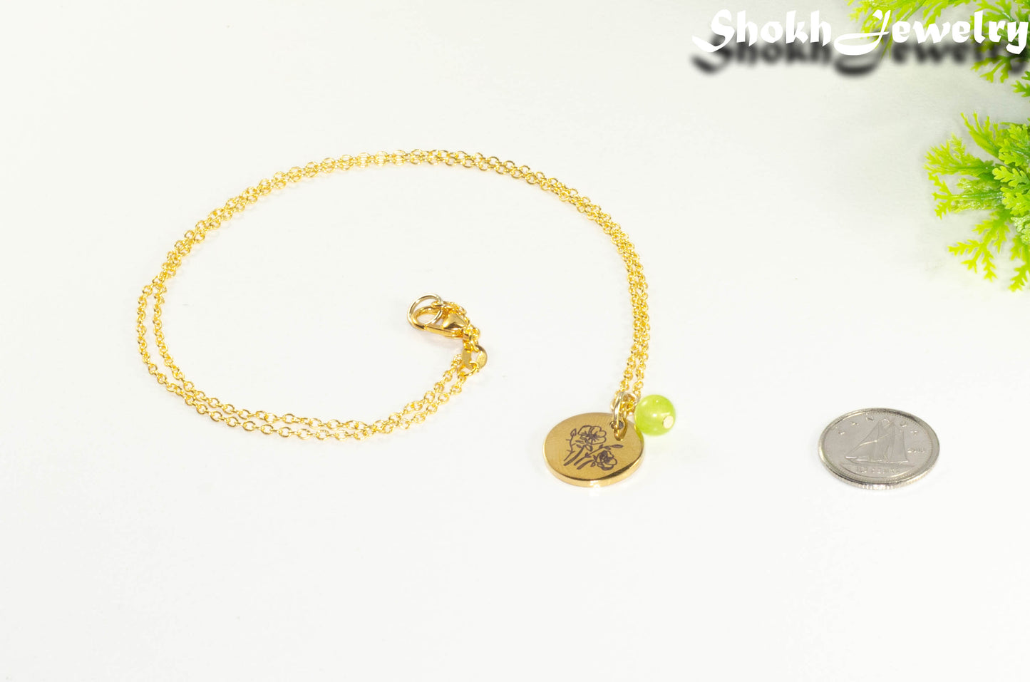 Gold Plated August Birth Flower Necklace with Peridot Birthstone Pendant beside a dime.