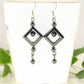 Long Black Hematite Geometric Earrings displayed on a tea cup.