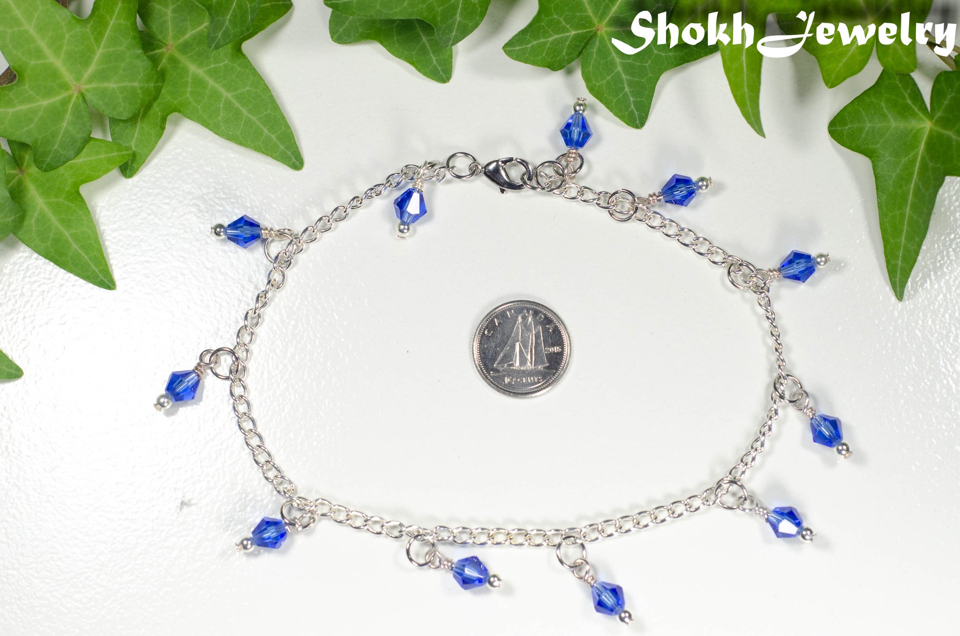 Navy Blue Glass Crystal Dangle and Chain Anklet beside a dime.
