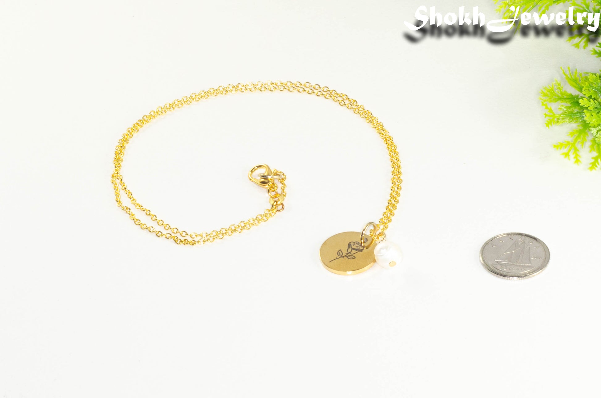 Gold Plated June Birth Flower Necklace with Freshwater Pearl Pendant beside a dime.