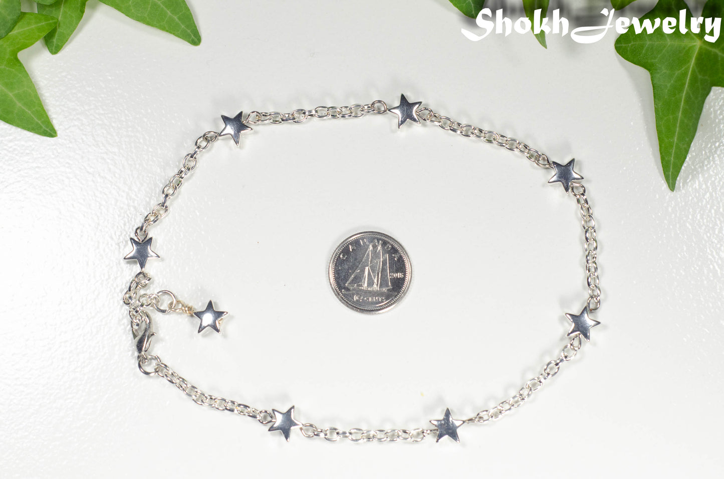 Silver plated Hematite Star and Chain bracelet beside a dime.