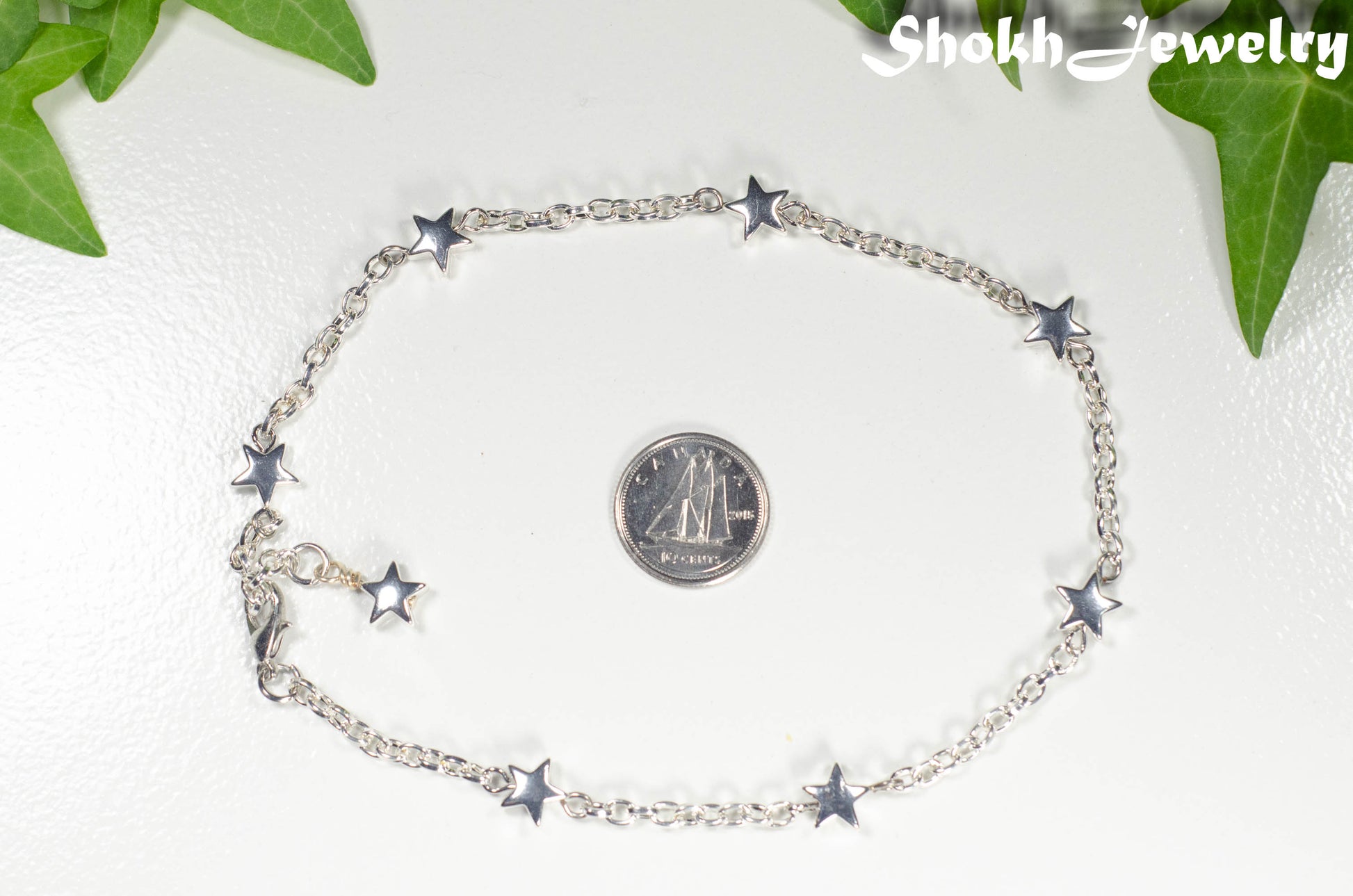 Silver plated Hematite Star and Chain bracelet beside a dime.