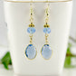 Light Blue Oval Glass Dangle Earrings displayed on a tea cup.