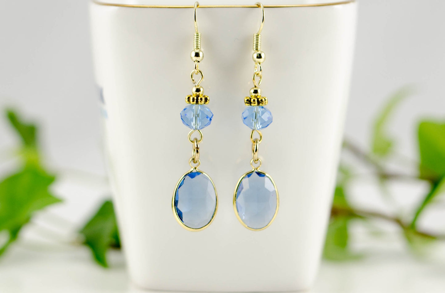 Light Blue Oval Glass Dangle Earrings displayed on a tea cup.