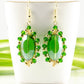 Oval Green Glass Crystal Wire Wrapped Earrings displayed on a tea cup.