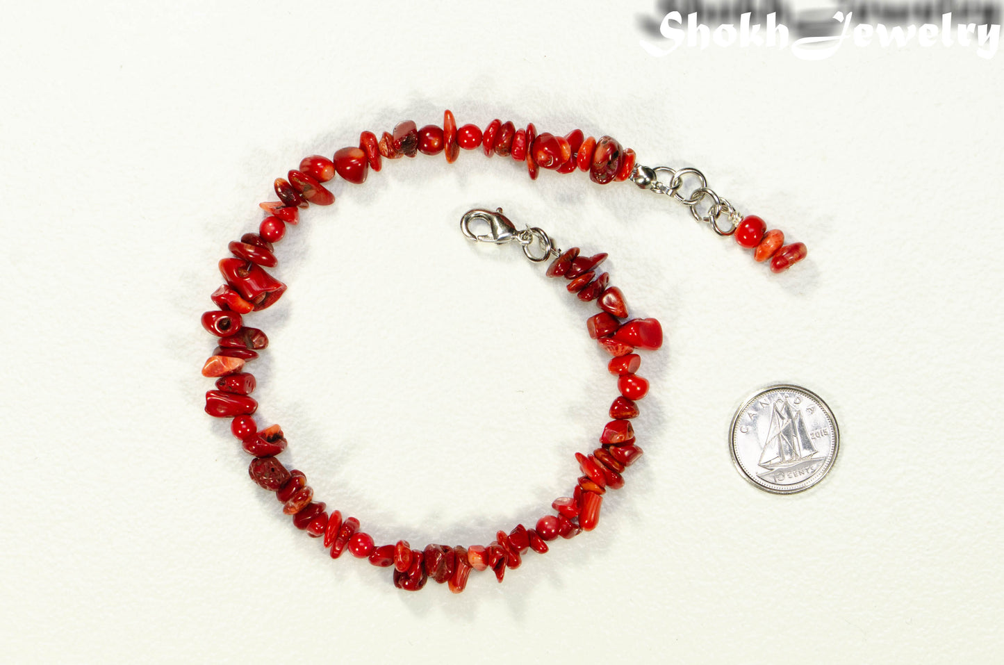 Natural Red Coral Chip Bracelet beside a dime.