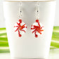 Christmas Peppermint Glass Bead Earrings displayed on a tea cup