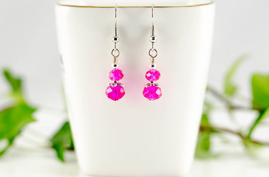Small Hot Pink Glass Bead Dangle Earrings displayed on a tea cup.