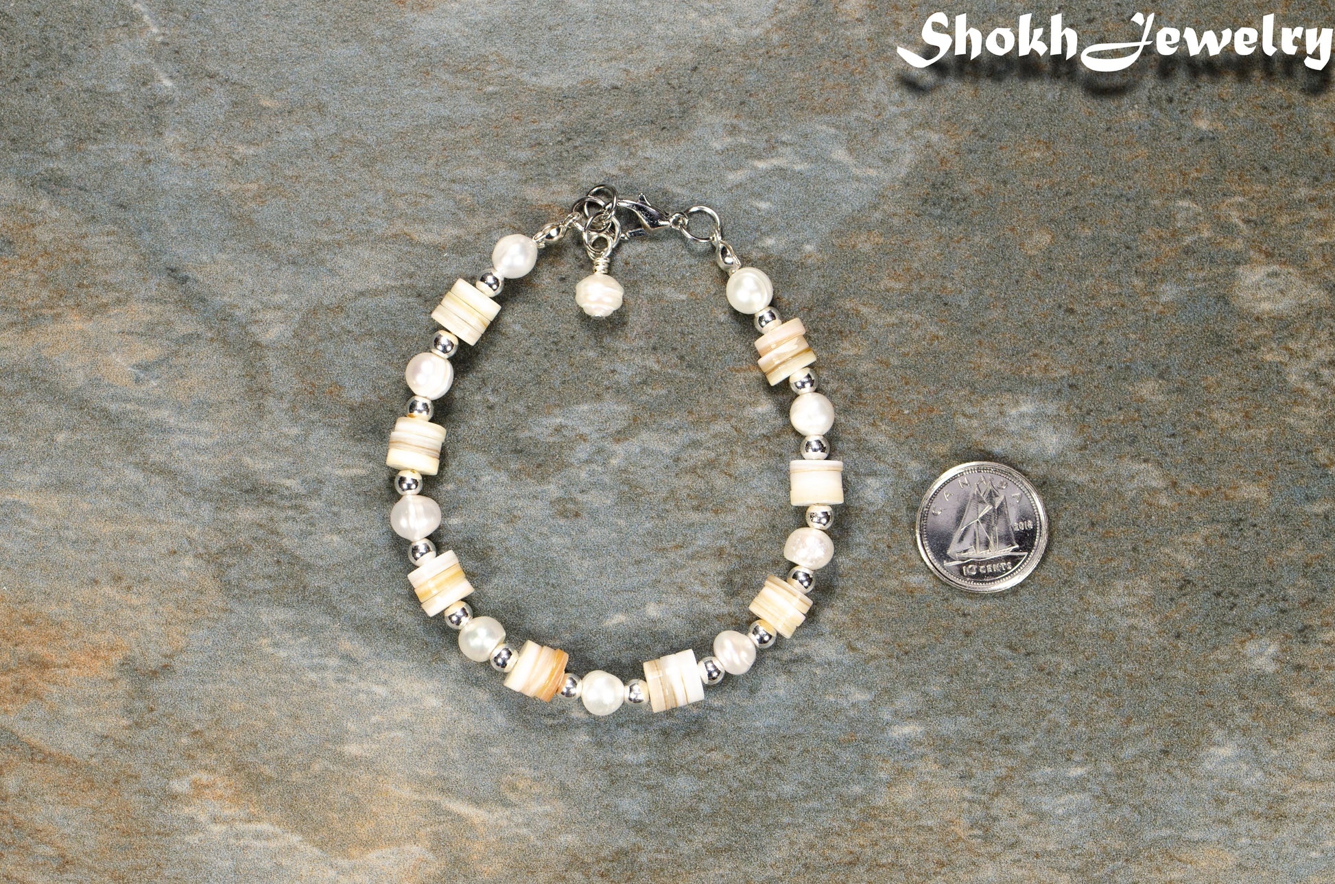 Freshwater Pearl and Seashell Bracelet with Clasp beside a dime.