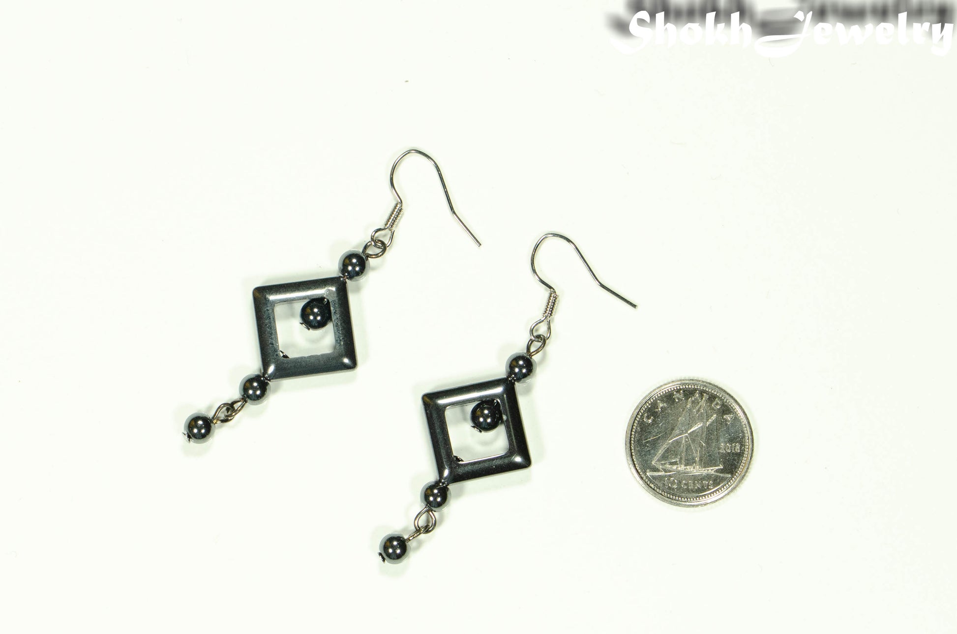 Long Black Hematite Geometric Earrings beside a dime.