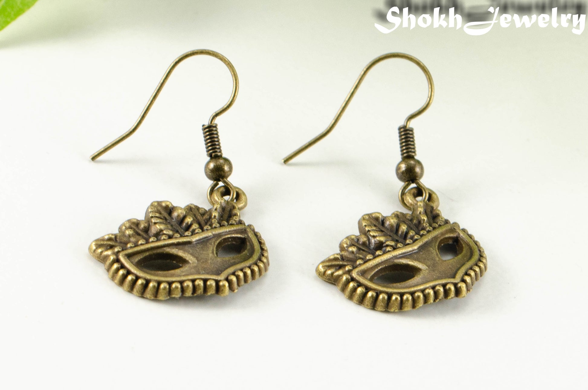 Close up of Antique Bronze Masquerade Mask Charm Earrings.