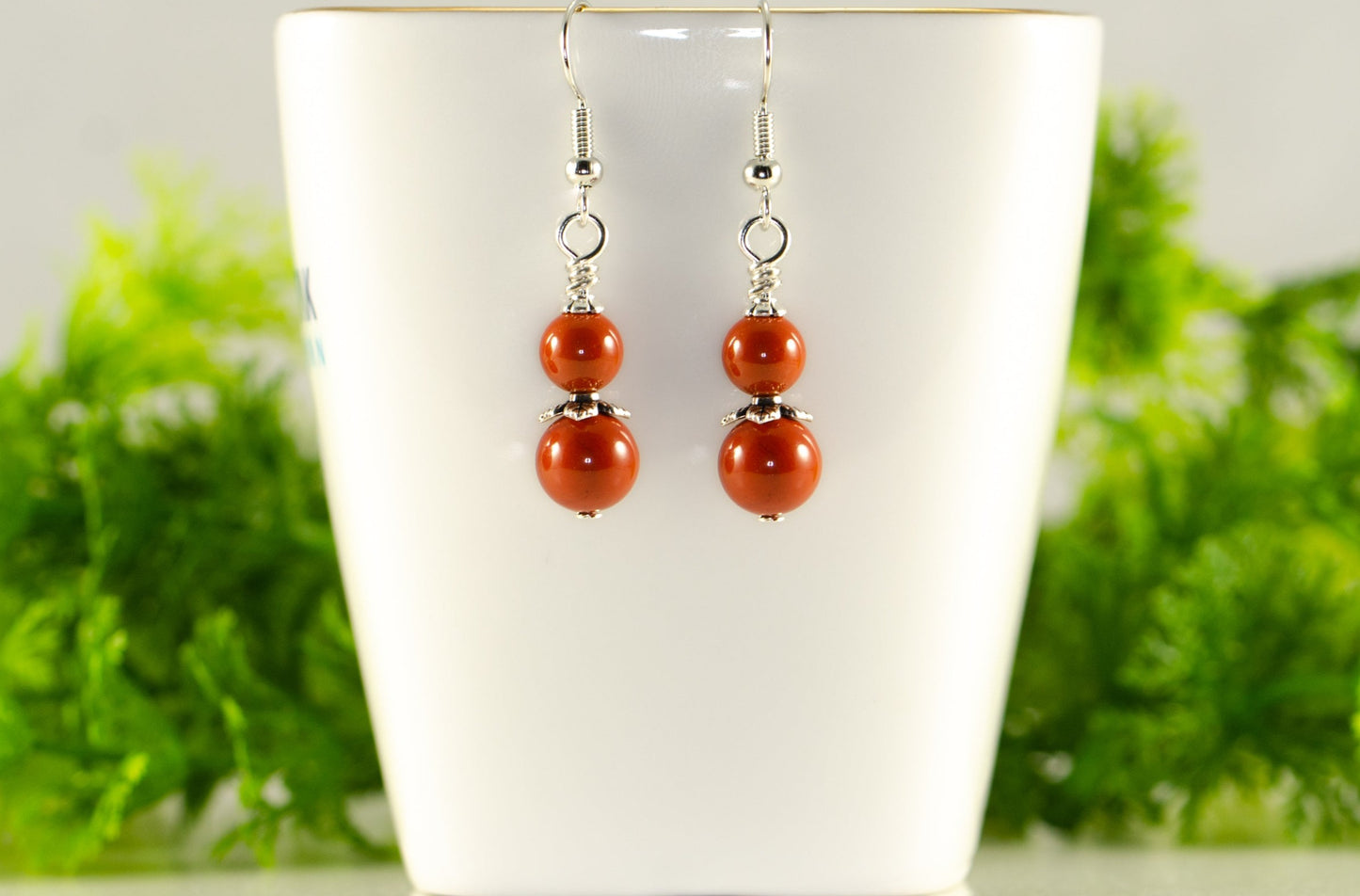 Small Natural Red Jasper Earrings displayed on a tea cup.