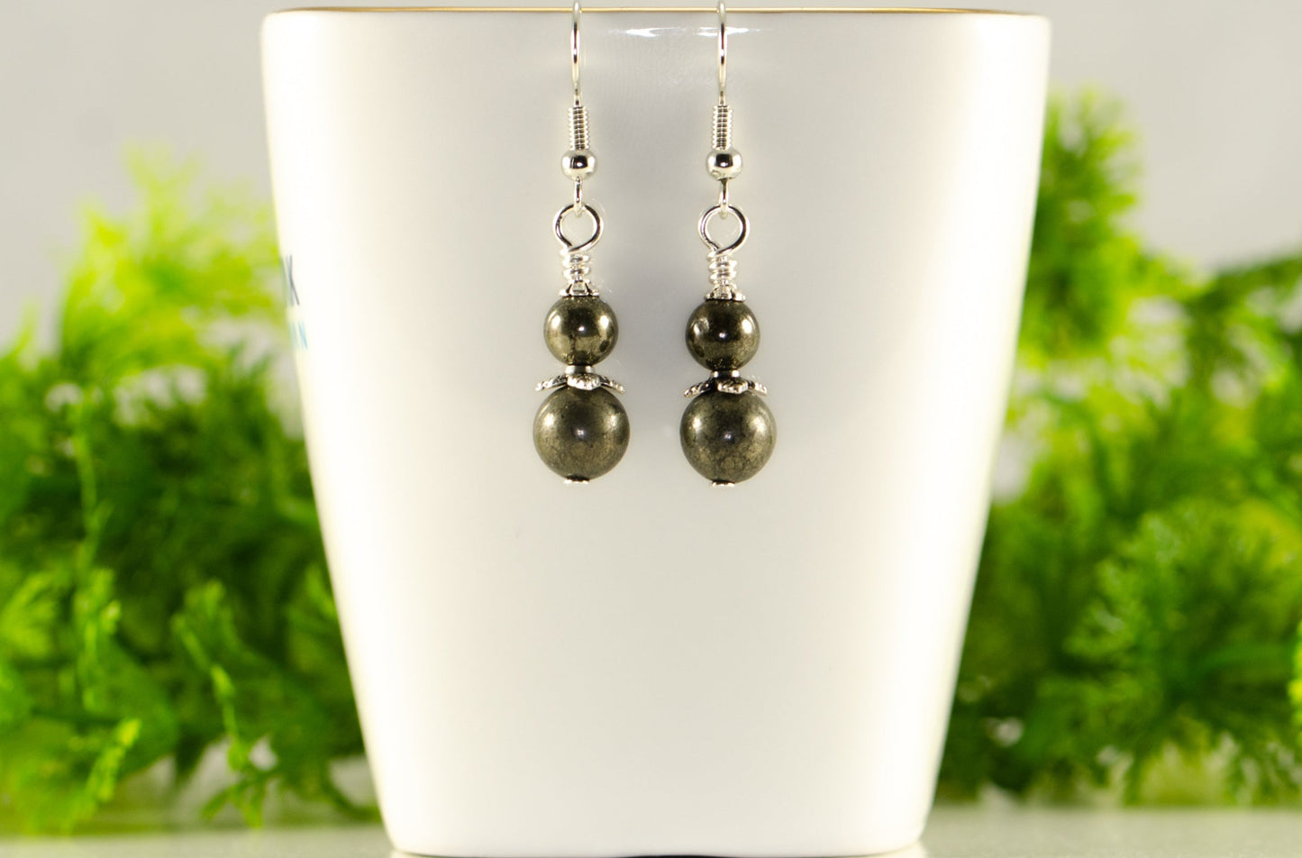 Small Natural Pyrite Earrings displayed on a tea cup.