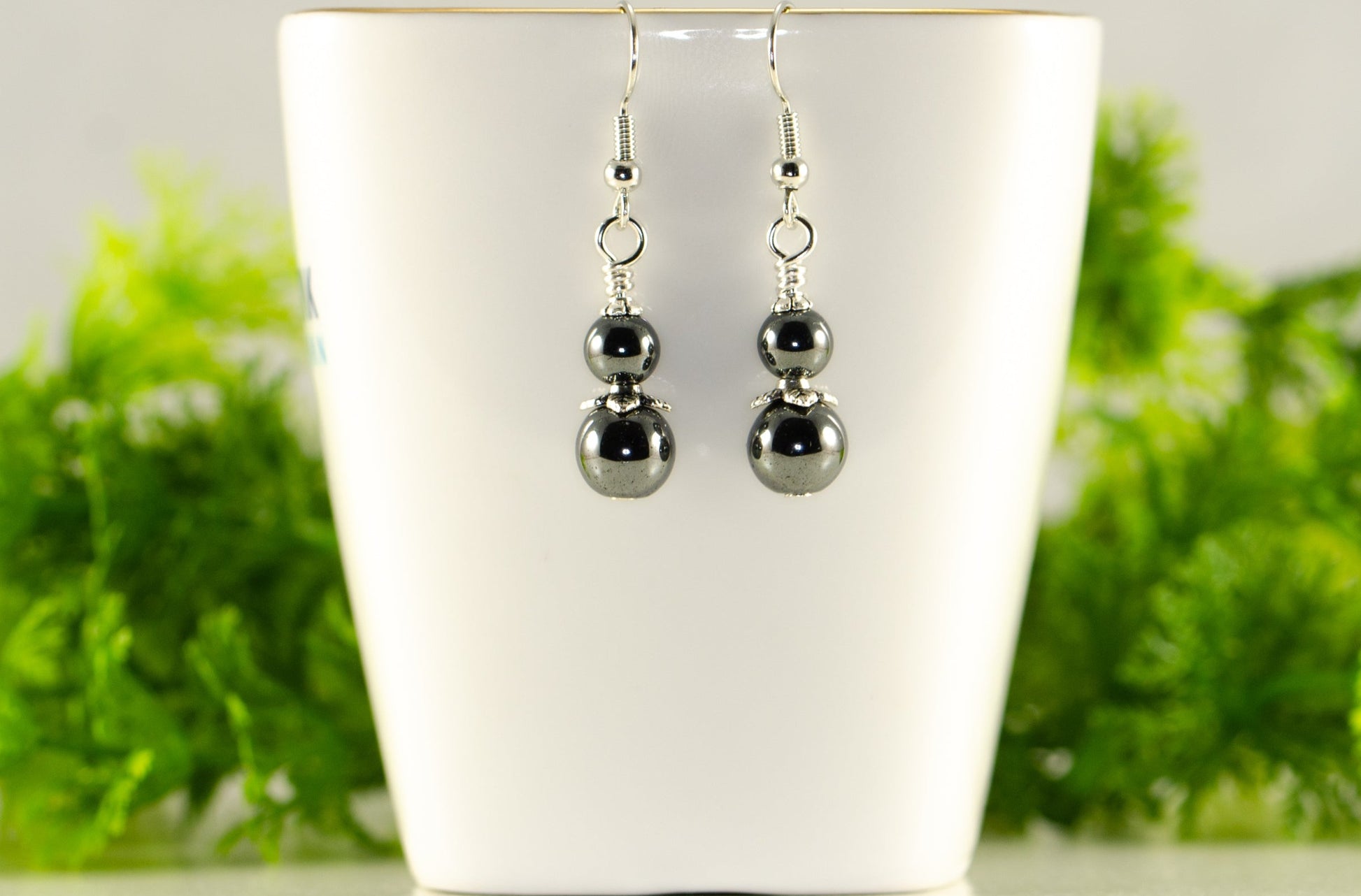 Small Natural Hematite Earrings displayed on a tea cup.