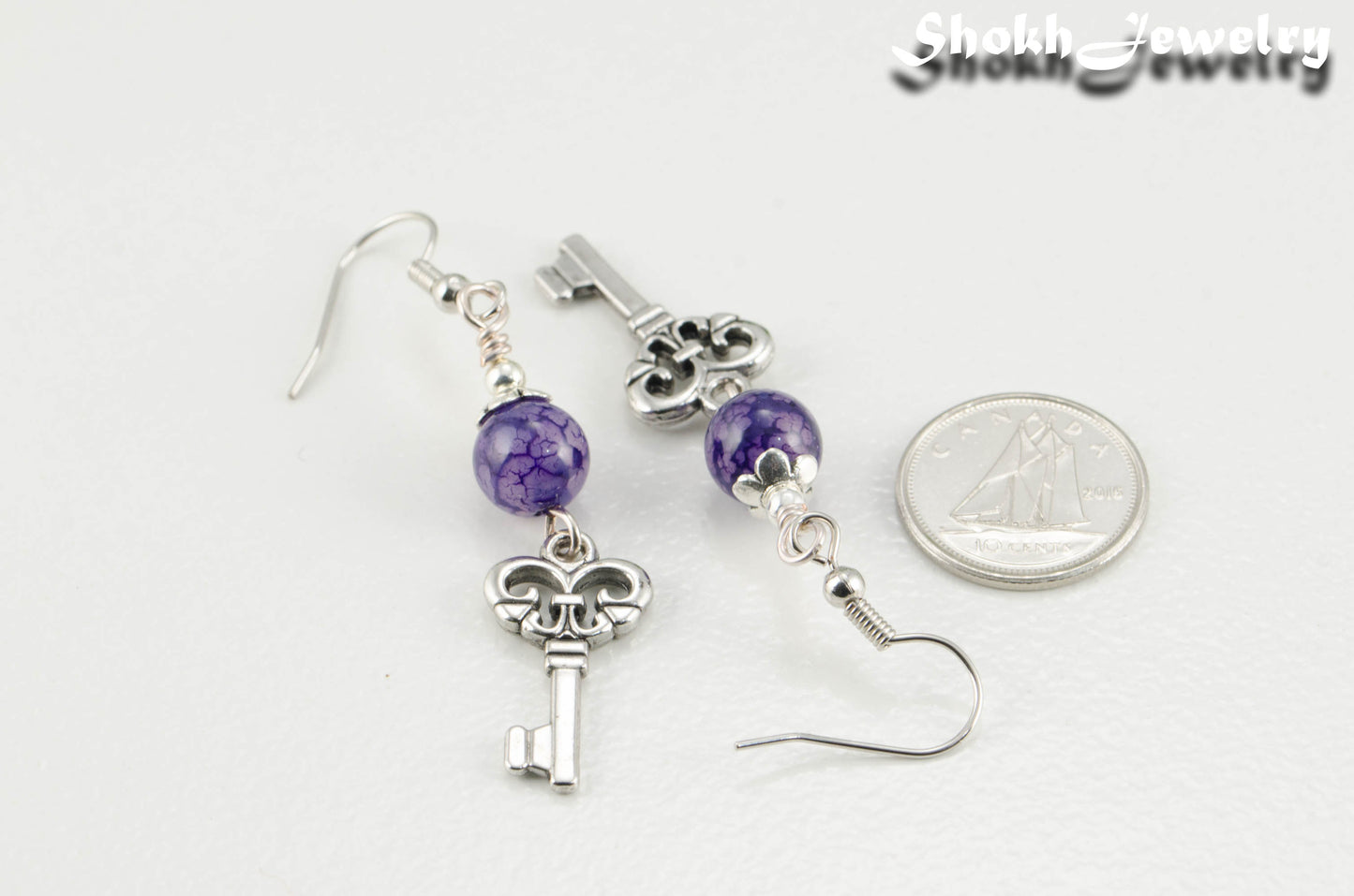 Purple Agate and Key Charm Dangle Earrings beside a dime.