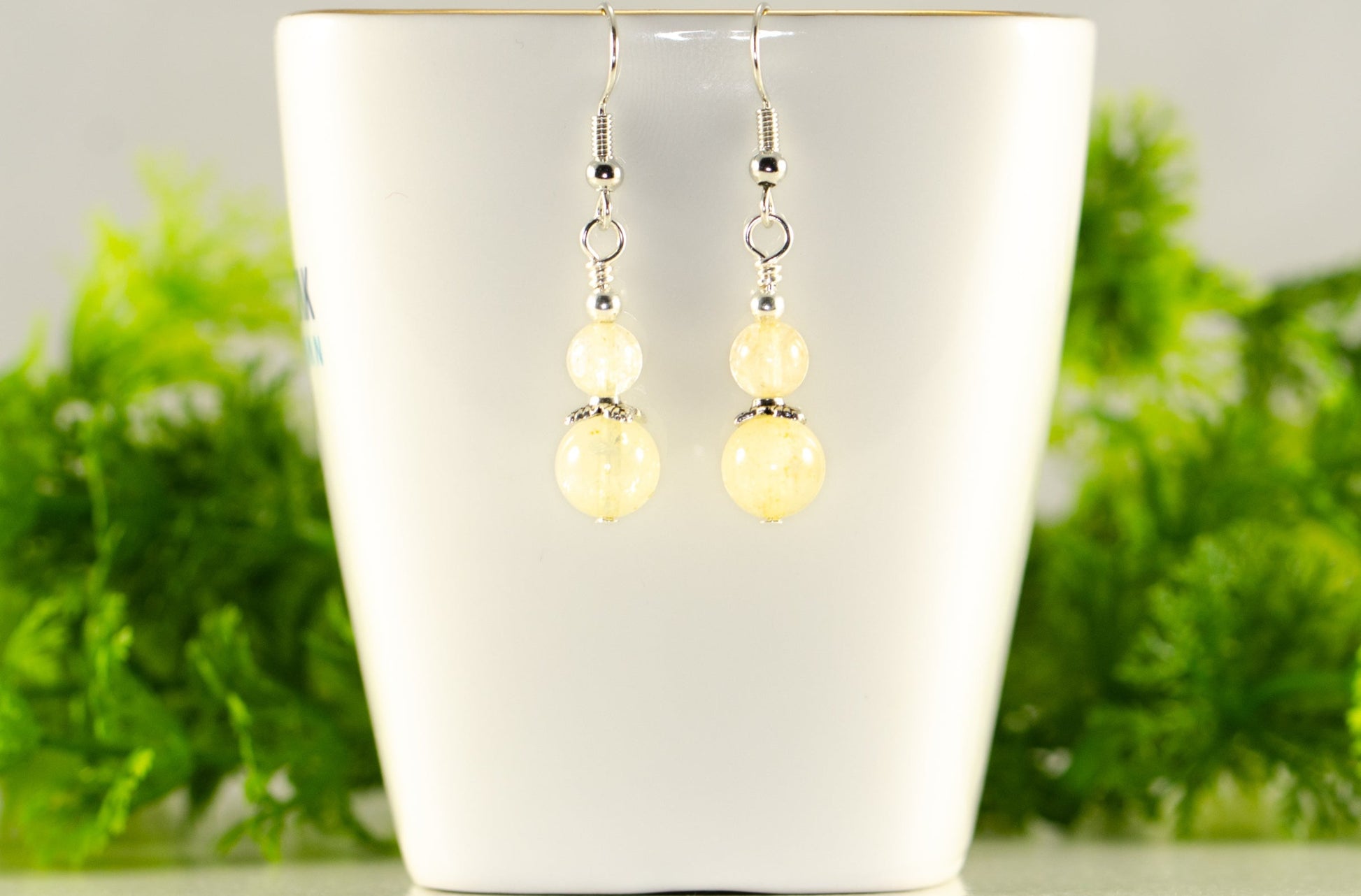 Small Natural Citrine Crystal Earrings displaed on a tea cup.