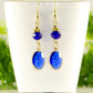 Navy Blue Oval Glass Dangle Earrings displayed on a tea cup.