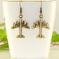 Antique Bronze 3D Plane Charm Earrings displayed on a tea cup.