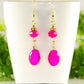 Hot Pink Oval Glass Dangle Earrings displayed on a tea cup.