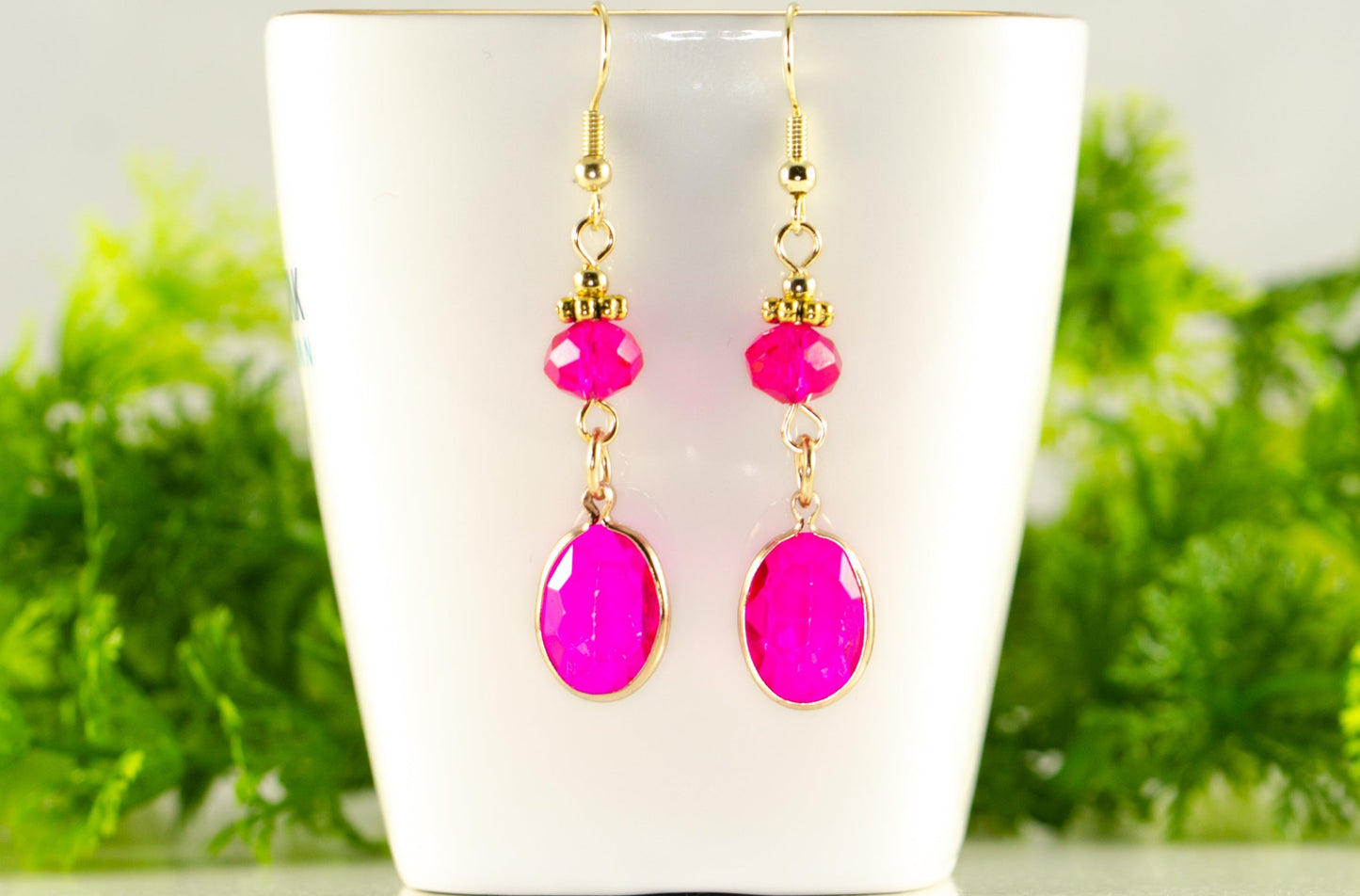 Hot Pink Oval Glass Dangle Earrings displayed on a tea cup.