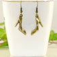 Antique Bronze High Heel Shoe Charm Earrings displayed on a tea cup.
