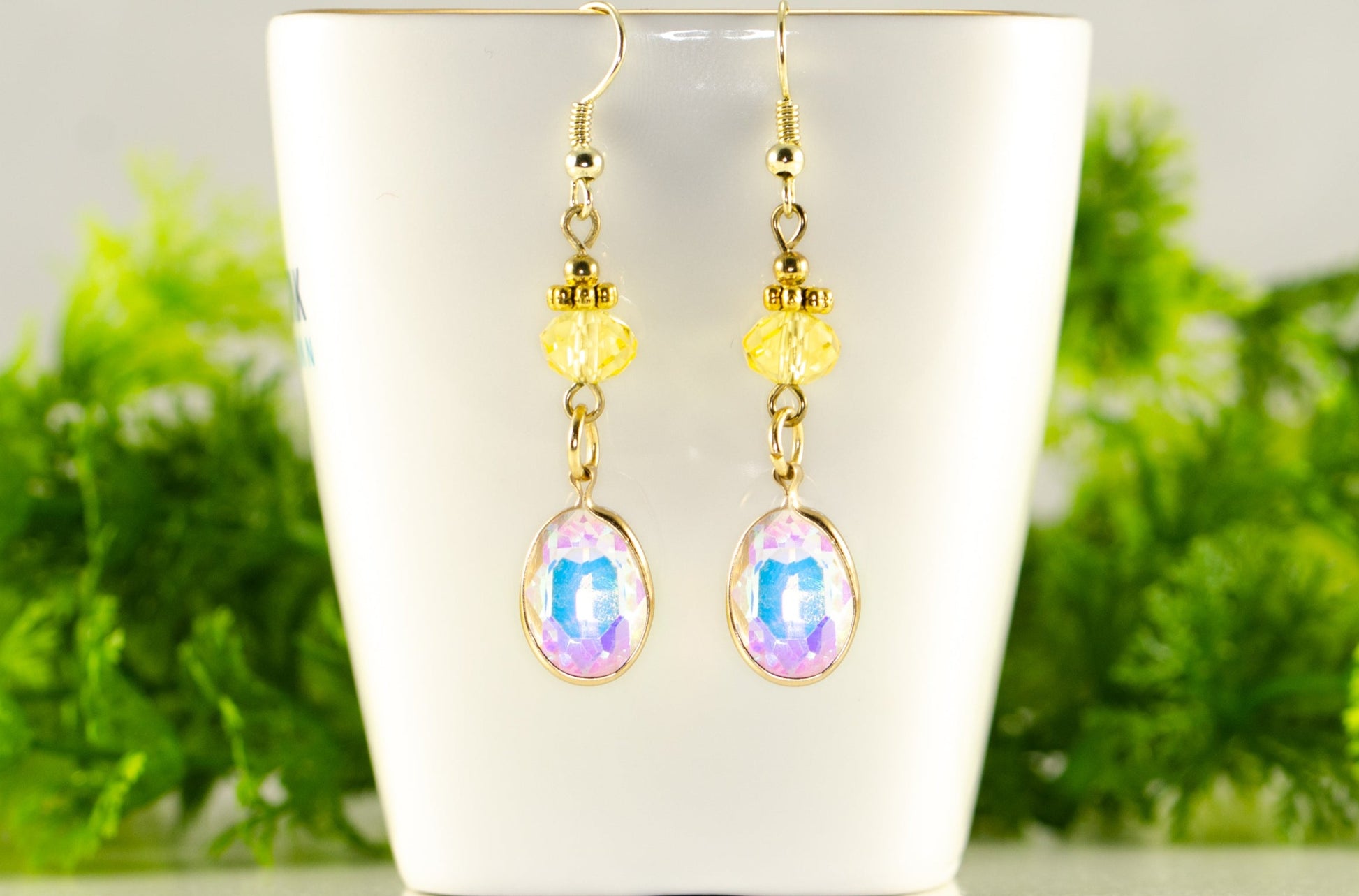 Light Yellow Oval Glass Dangle Earrings displayed on a tea cup.