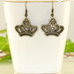 Antique Bronze Crown Charm Earrings displayed on a tea cup.