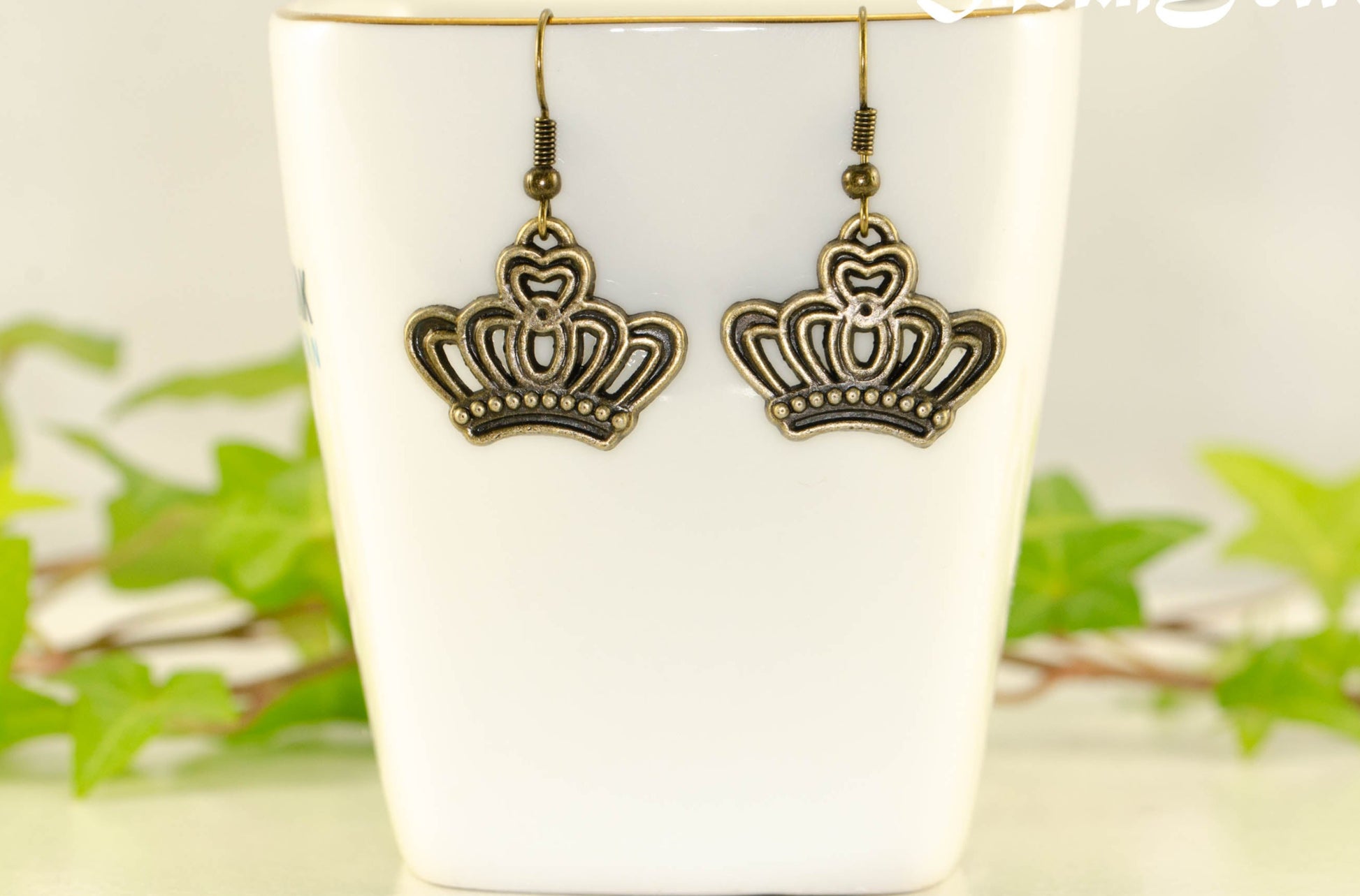 Antique Bronze Crown Charm Earrings displayed on a tea cup.