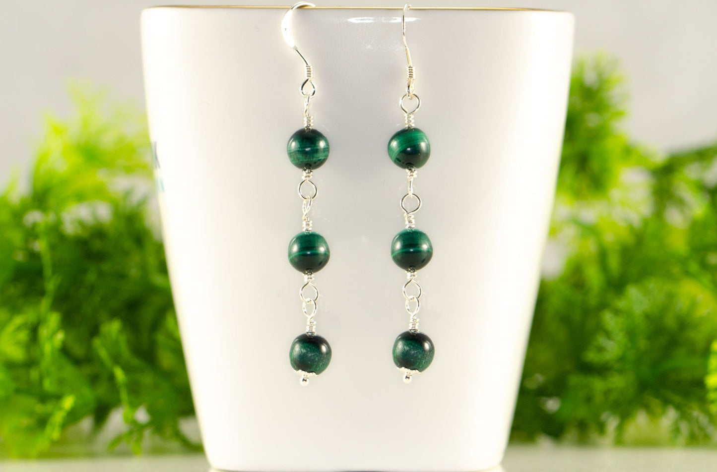 Long Genuine Malachite Dangle Earrings displayed on a tea cup.