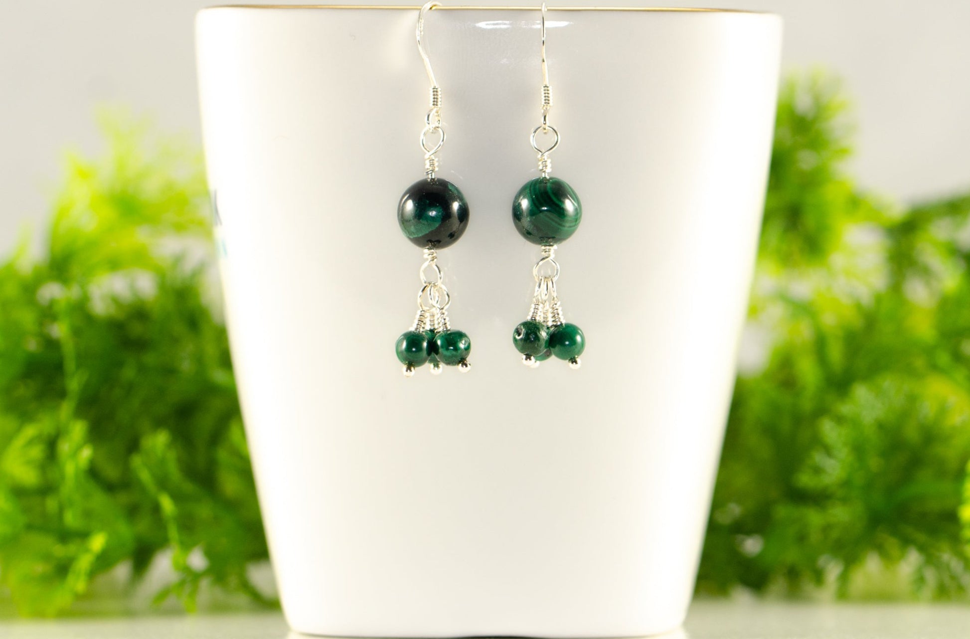 Genuine Malachite Dangle Earrings displayed on a tea cup.