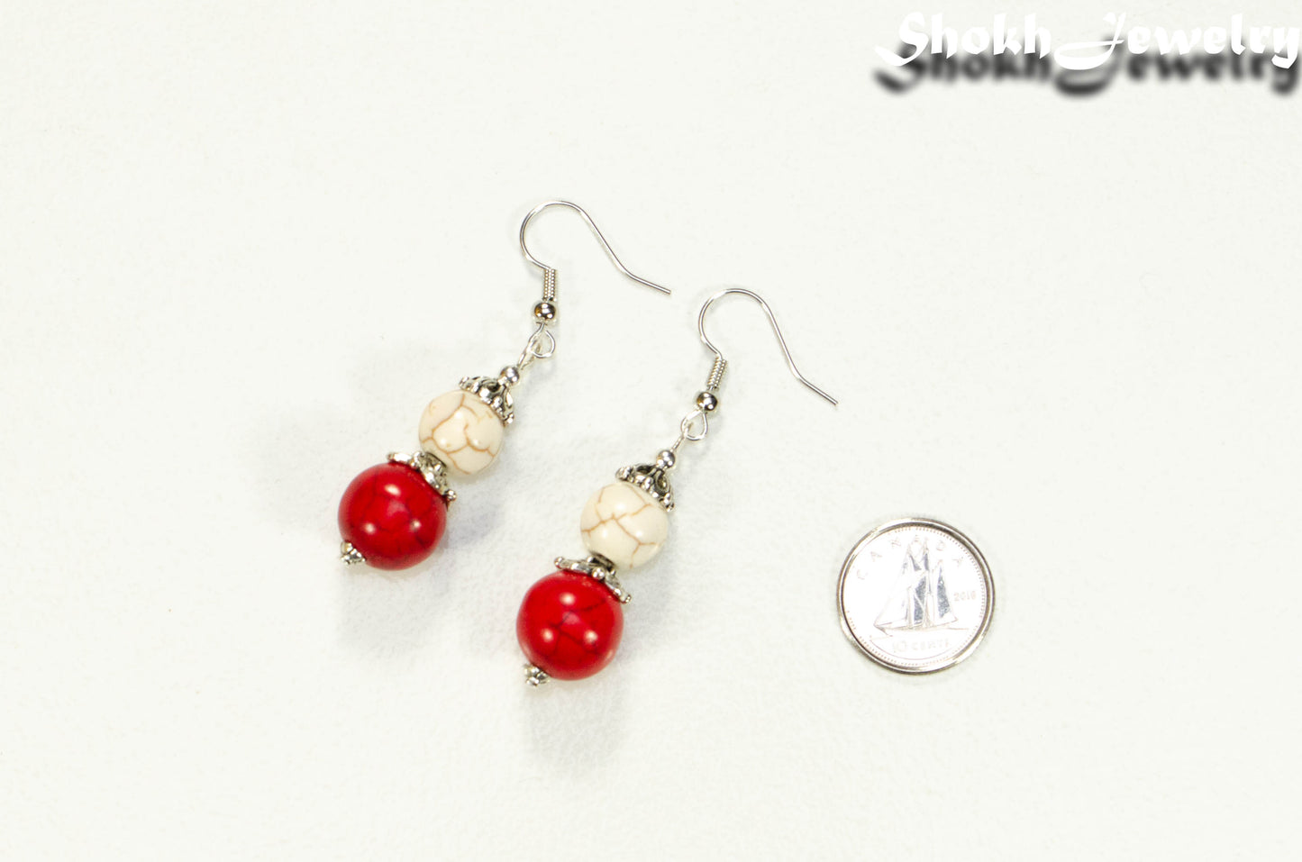 Red and White Howlite Dangle Earrings beside a dime.