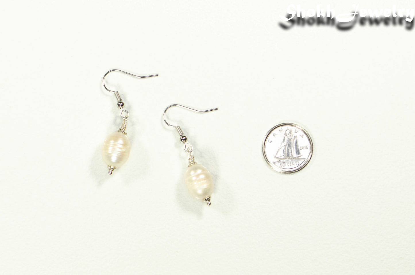 12mm Natural Freshwater Pearl Earrings beside a dime.
