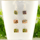 Long Unakite Cube Dangle Earrings displayed on a tea cup.