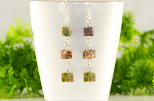 Long Unakite Cube Dangle Earrings displayed on a tea cup.