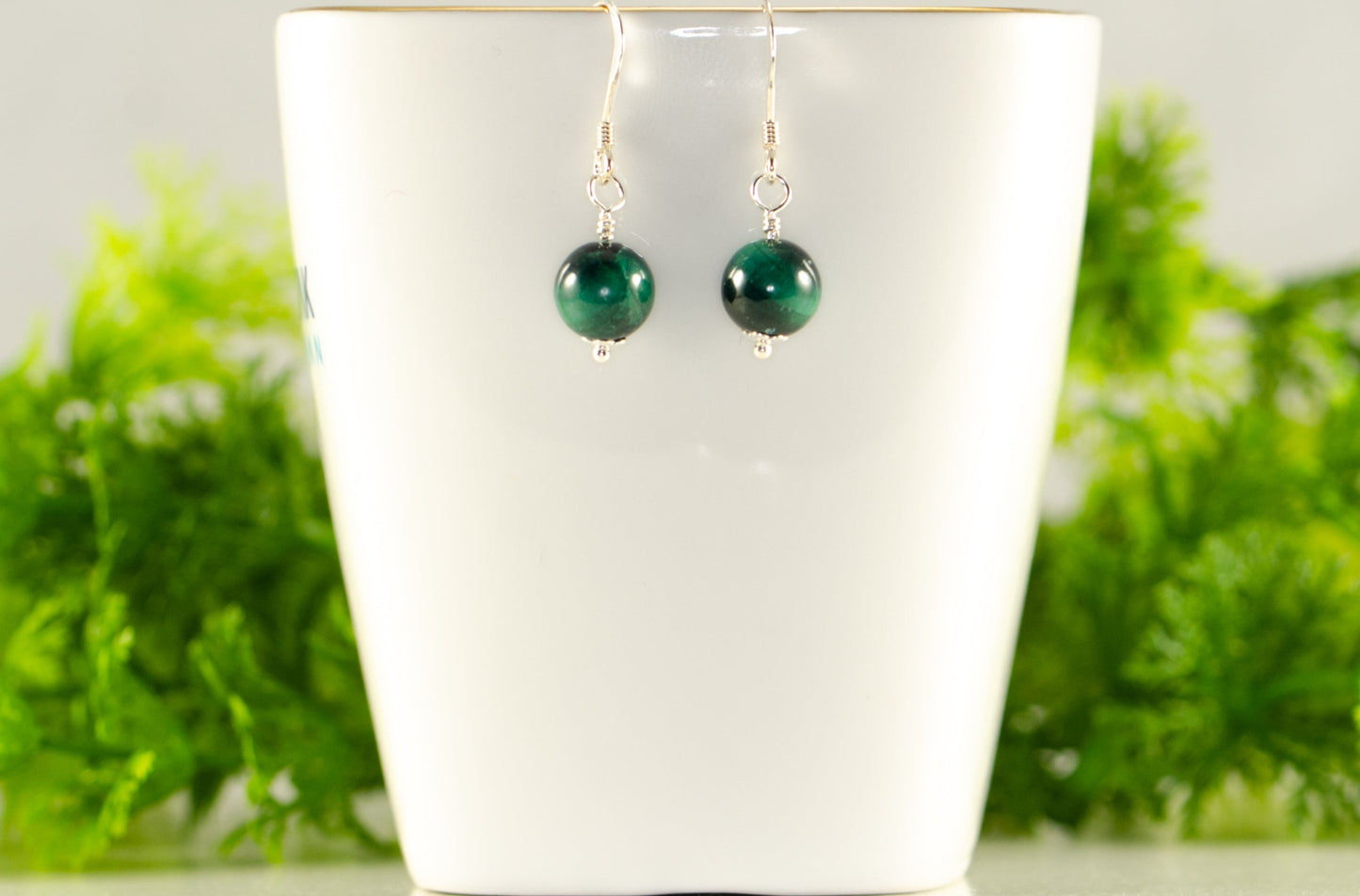 Small Genuine Malachite Drop Earrings displayed on a tea cup.