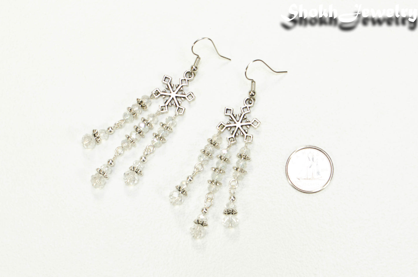 Clear Glass Crystal Chandelier and Snowflakes Earrings beside a dime.