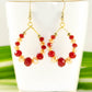 Red and Gold Glass Crystal Hoop Earrings displayed on a tea cup.