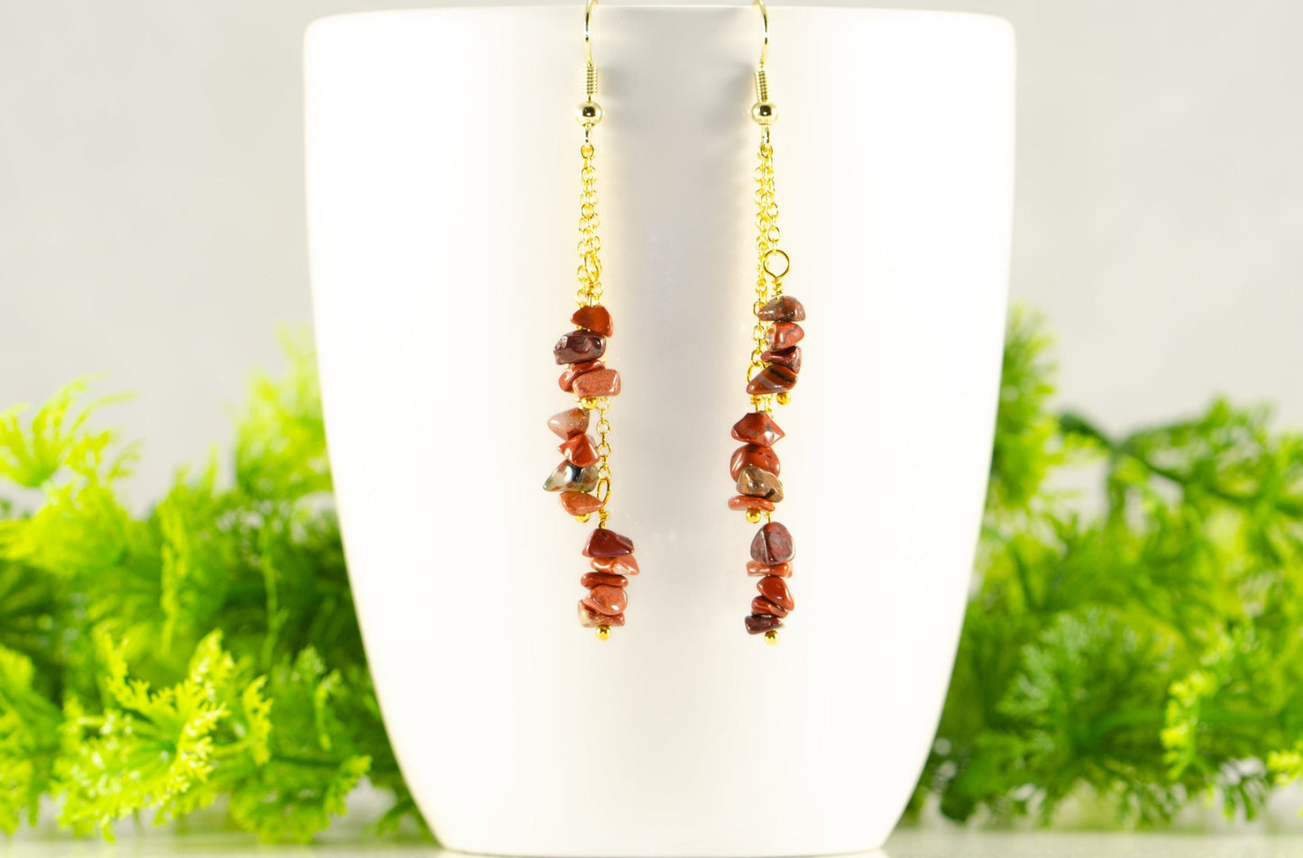 Long Gold Plated Chain and Red Jasper Chip Earrings displayed on a coffee mug.